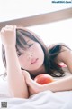 A woman laying on a bed holding an apple.