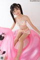 A young girl in a bikini sitting on an inflatable flamingo.