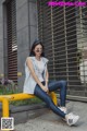 A woman sitting on a yellow bench in front of a building.