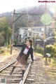 A woman in a school uniform is standing on a train track.