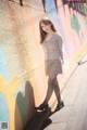 A woman leaning against a wall with a colorful wall behind her.