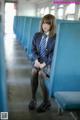 A woman in a school uniform sitting on a train.