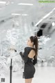 A woman in a black dress standing in front of a white tree.