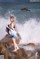 A woman standing on a rock by the ocean.