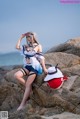 A woman sitting on top of a rock next to the ocean.