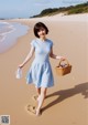 A woman walking on the beach holding a basket.