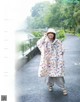 A woman wearing a rain poncho standing in the rain.