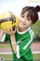 A young woman holding a soccer ball on a field.