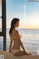 A woman in a white bikini sitting on a window sill.