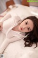 a woman laying on top of a bed in a white shirt