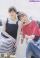 Two young women sitting on a white chair in a field.