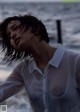 A woman in a white shirt standing on the beach.