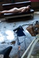 A naked woman laying on a bench next to a bike.