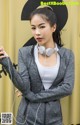 A woman wearing headphones standing in front of a yellow wall.