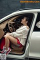 A woman sitting in the driver's seat of a car listening to music.