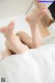 A woman laying on top of a bed with her feet up.