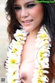 A woman wearing a flower lei on the beach.