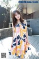 A woman in a colorful dress standing on a wooden deck.