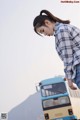 A woman leaning on the back of a blue and white bus.