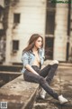 A woman sitting on a ledge in front of a building.